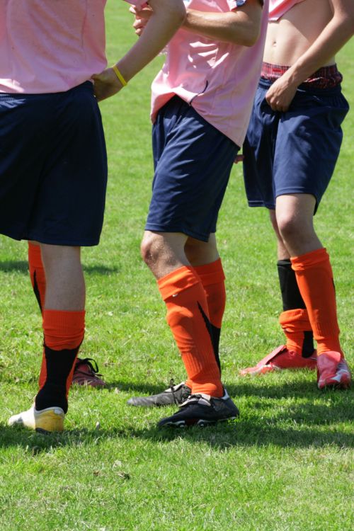 Fußballspieler in orange-schwarzen Stutzen und blauen Shorts auf dem Sportplatz Donnerskirchen.